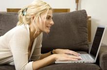 Picture of a woman lying on the couch, while she's playing games